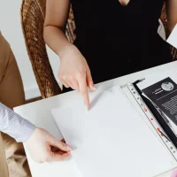 Two people reviewing and pointing at printed pages in a folder